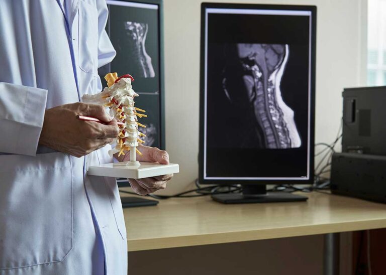 A chiropractor gently performing a spinal adjustment on a fully clothed adult patient in a clinic setting.