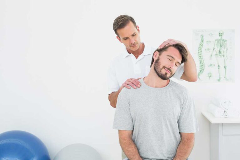 Adult resting in bed with a supportive pillow while a clinician reviews a spine and sleep diagram nearby.