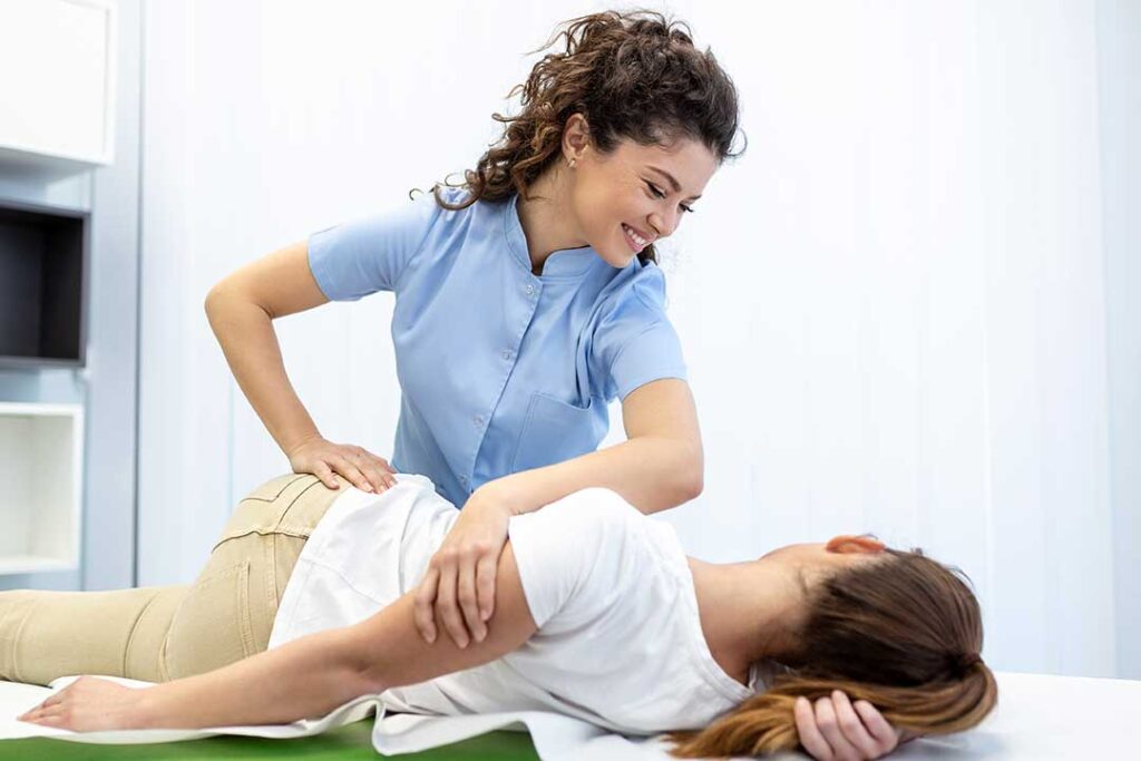 Older adult practicing balance beside a sturdy chair while a clinician observes movement.