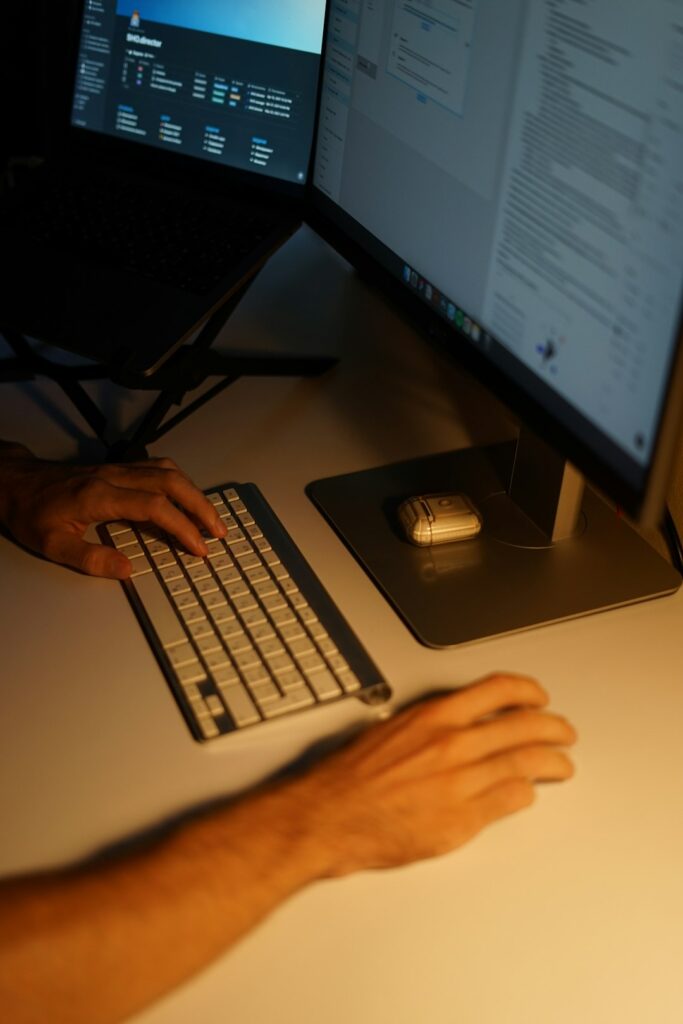 Person gently stretching a wrist beside a desk with a neutral-position wrist splint and relaxed hand posture.